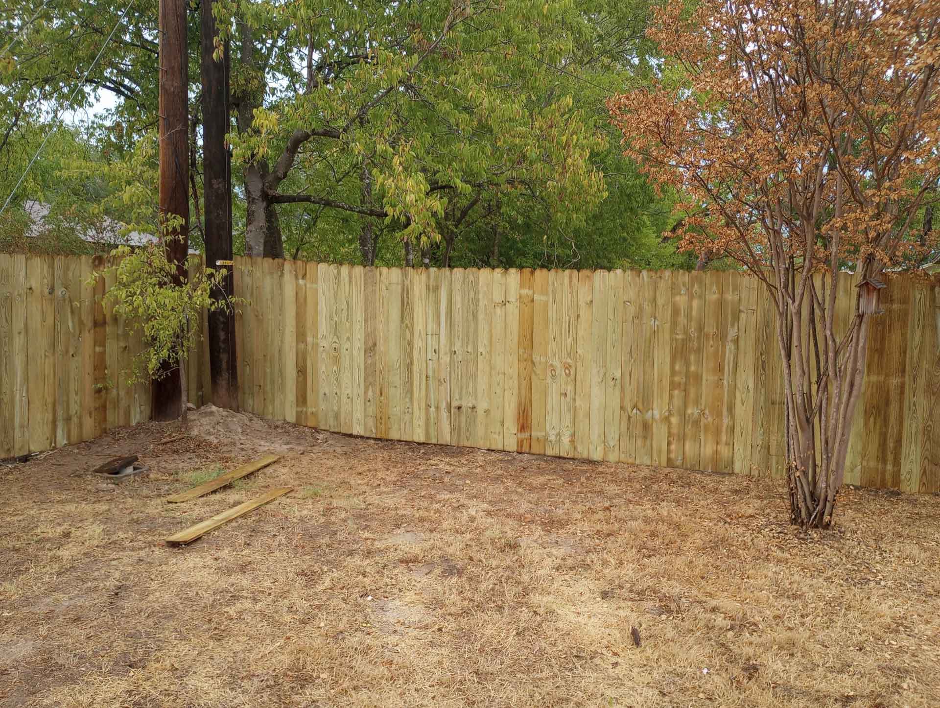 A wooden fence in a backyard with some power lines